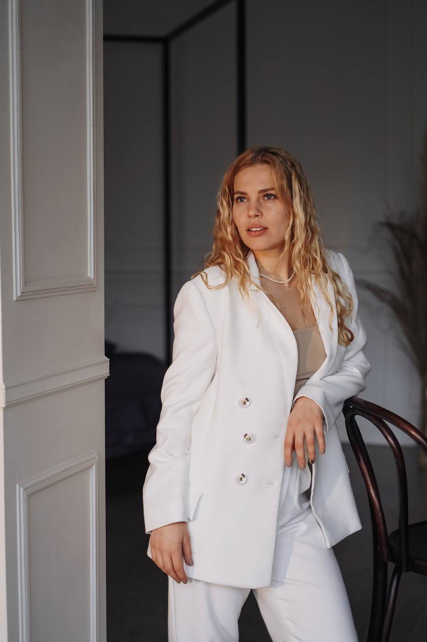 Лана Тельминова в светлом костюме у дверного проёма
